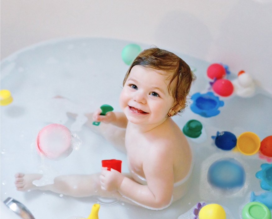 A child playing with colorful water balls in a bath