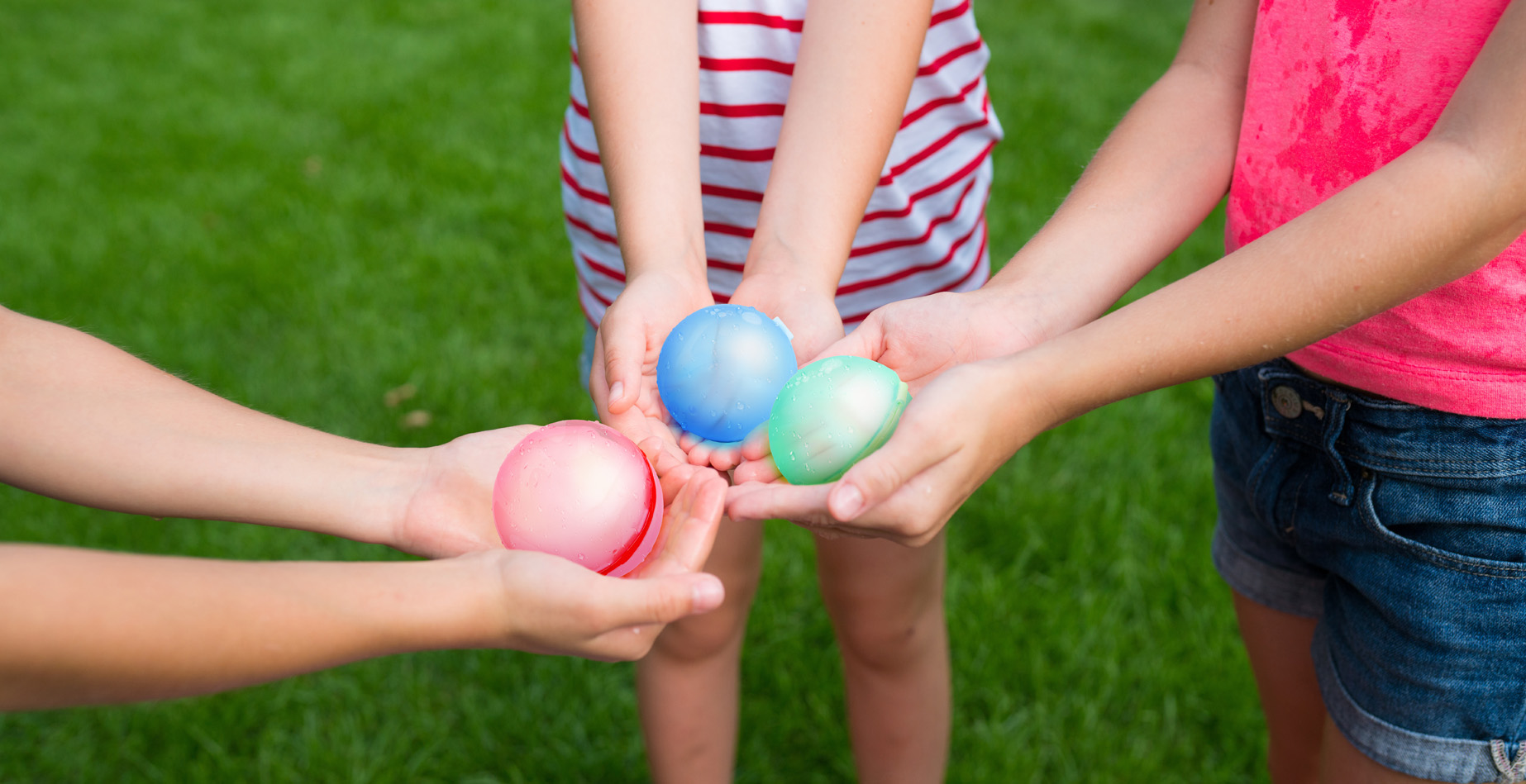 Children holding blue, green and red reusable water balls together