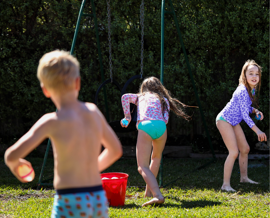 Children playing with water balls outdoors in summer